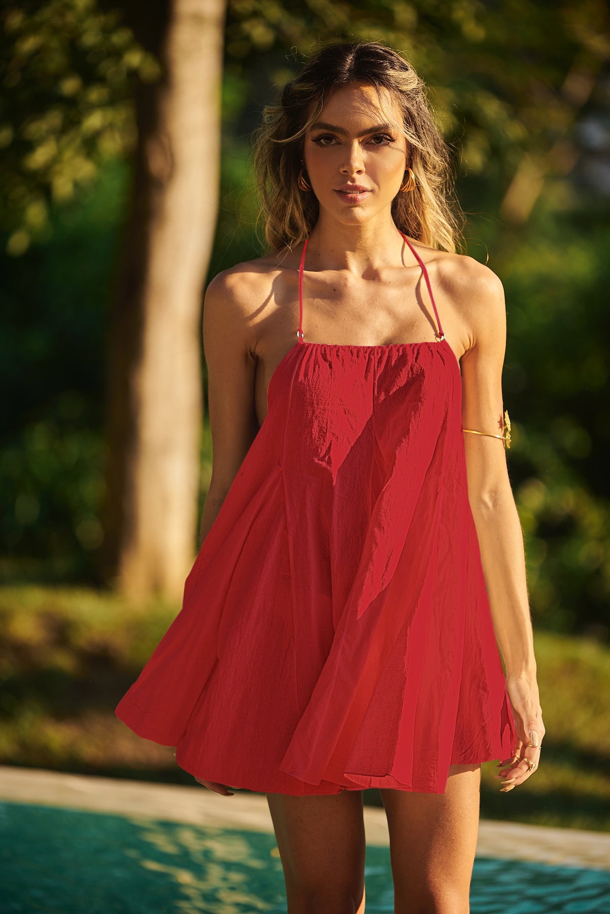 Model posing by the pool in a red Lonarc beachwear dress